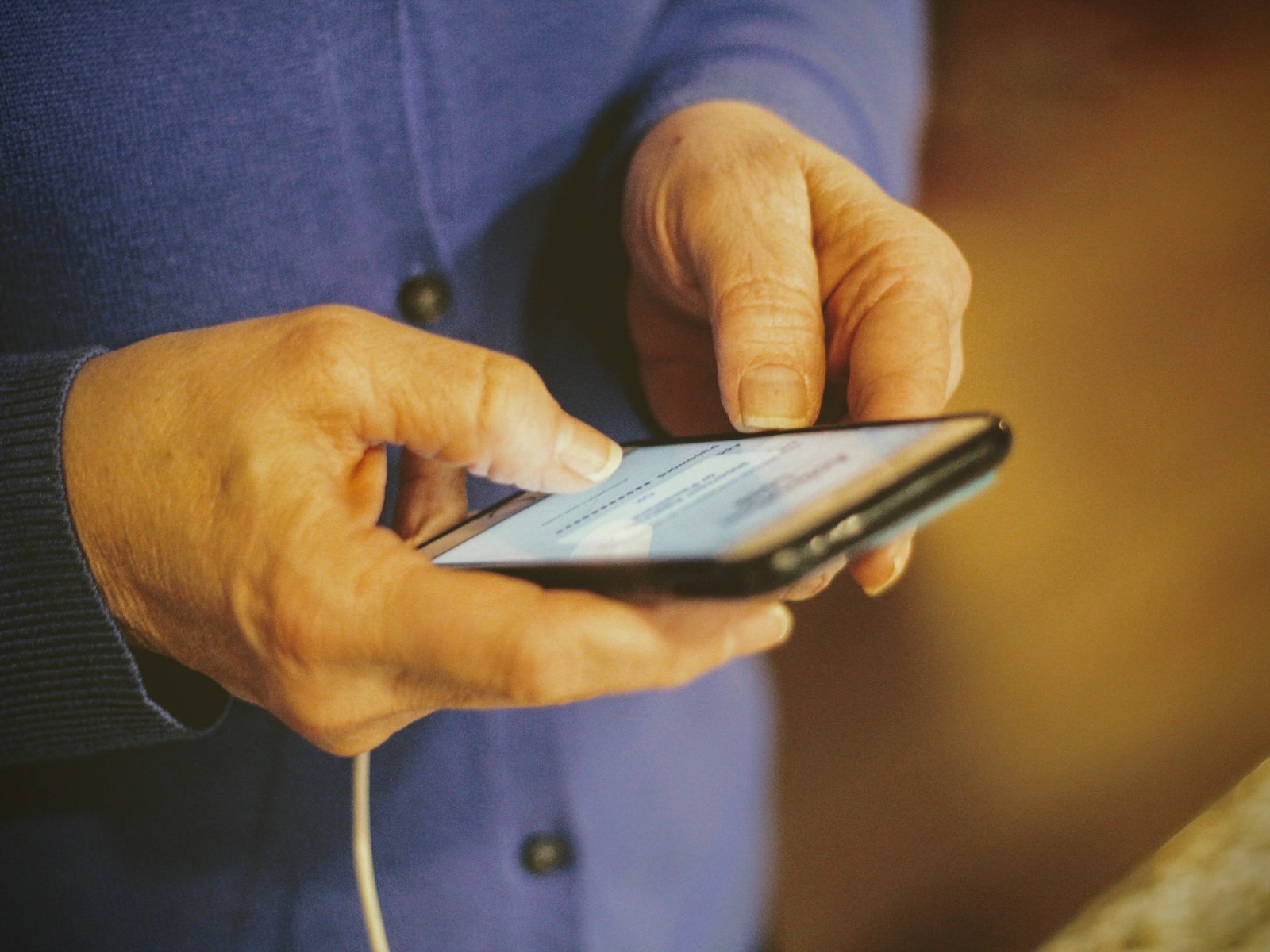 Ældre persons hænder bruger en smartphone